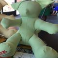 A green teddy bear sitting on top of a table.
