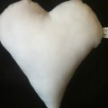 A white heart pillow on top of black background.