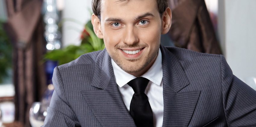 A man in suit and tie sitting at table.