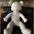 A large white teddy bear sitting on top of a black couch.